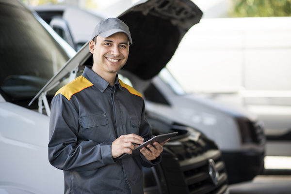 Mechanic using a tablet in front of a van
